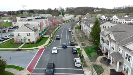 Aerial-tracking-shot-of-Tesla-Model-Y-driving-through-modern-apartments-in-USA-suburb-during-spring