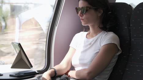 Woman-using-smartphone-and-ebook-on-train,-scenic-journey
