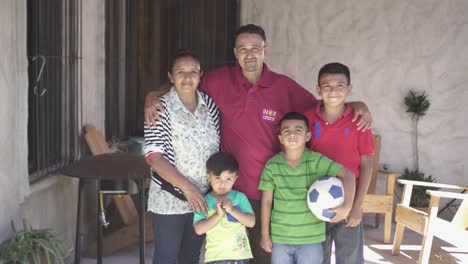 Honduran-family-poses-smiling-for-camera-in-front-of-their-house