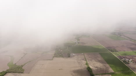 Aerial-drone-moves-through-clouds-above-grassland-and-farmland-in-midwest-of-United-States