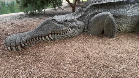 Giant-Crocodile-Dinosaur-Sculpture-in-Kings-Park,-Perth-Western-Australia-by-water