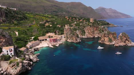 Erstaunliche-Luftaufnahme-Eines-Rosafarbenen,-Malerischen-Hauses-An-Der-Felsigen-Mittelmeerküste-In-Sizilien,-Italien