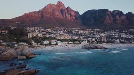 Drohne-Fliegt-über-Camps-Bay-Beach-Und-Zeigt-Mehr-Von-Der-Küstenregion-Bei-Sonnenuntergang-In-Kapstadt,-Südafrika