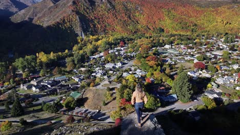 Blonde-model-girl-is-looking-at-village-covered-by-colourful-trees