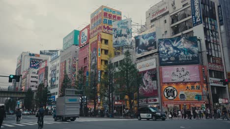 Fußgänger,-Autos-Und-Geschäftsgebäude-Mit-Werbetafeln-In-Der-Stadt-Tokio,-Japan