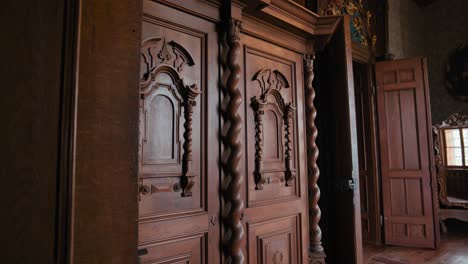 Count-Bedroom-in-Trakošćan-Castle,-featuring-intricately-carved-wooden-doors-with-twisted-columns-and-decorative-panels,-reflecting-the-room-in-an-ornate-mirror