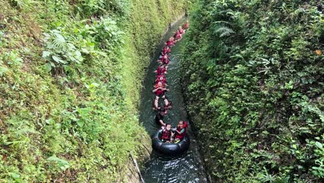 People-wearing-life-jackets-and-floating-in-a-row-on-mountain-river