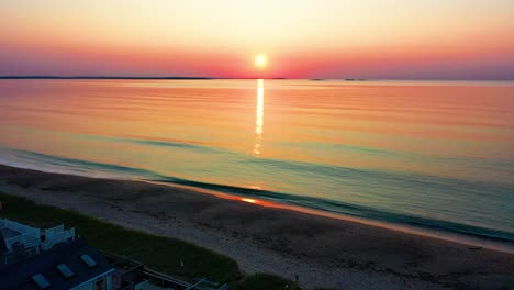 Luftaufnahme-Von-Wunderschönen-Strandhäusern-Und-Sonnenaufgang-über-Ferienhäusern-In-Maine-Und-Farben,-Die-Sich-In-Den-Meereswellen-Entlang-Der-Atlantikküste-Von-Neuengland-Spiegeln