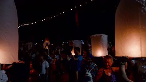 Touristen-Halten-Aufgeregt-Schwebende-Laternen-In-Der-Hand,-Bevor-Sie-Diese-Während-Des-Yi-Peng-Festivals-In-Chiang-Mai,-Thailand-In-Den-Nachthimmel-Entlassen