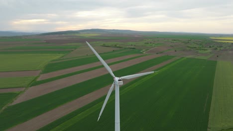 Hoch-Aufragende-äolische-Windturbinen-über-Grünen-Feldern-Im-Sonnenaufgang