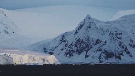 Glaciar-Y-Montañas-En-La-Costa,-Paisaje-Montañoso-Antártico-De-Paisaje-Costero,-Escena-Azul-De-Invierno-Con-Hielo-Y-Agua-De-Mar-Oceánica,-Paisaje-Marino-De-La-Península-Antártica-En-Una-Hermosa-Escena-Dramática