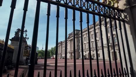 Peering-through-iron-gates-with-Buckingham-Palace-in-the-background-in-London,-England