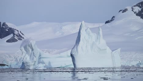 Big-Large-Iceberg-Ice-Formations-in-Sea,-Floating-in-Antarctica-Ocean-Sea-Water-in-Beautiful-Antarctic-Peninsula-Winter-Scenery,-Amazing-Nature-in-Coastal-Coast-Scene-of-Massive-Bizarre-Huge-Icebergs