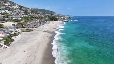 waves-crashing-on-Aliso-Beach-Southern-California-bright-sunny-day-large-mansion-homes-along-the-beach-and-hills-people-relaxing-on-the-beach-60fps