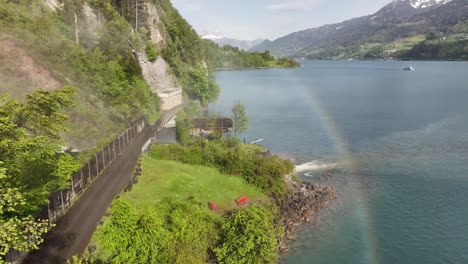 Vista-Aérea-De-Las-Cataratas-Seerenbach-Cerca-De-Amden-Betlis-Con-Un-Vibrante-Arco-Iris-Sobre-Walensee-Y-La-Exuberante-Vegetación-Circundante-En-Suiza