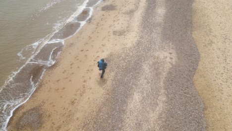 Aerial-view-of-a-tourist-with-backpack-walking-on-Kessingland-Beach-in-Suffolk,-England