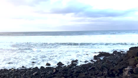 Olas-Espumosas-Blancas-De-Playa-Rocosa,-Toma-Panorámica-En-Cámara-Lenta