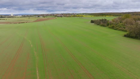 Drone-shot-over-a-cultivated-field-and-a-French-village-in-the-distance