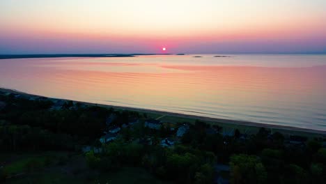 Luftaufnahme-Eines-Sonnenuntergangs-über-Strandhäusern-Mit-Farbenfrohen-Spiegelungen-Der-Meereswellen-Und-Ferienhäusern-Entlang-Der-Atlantikküste-Neuenglands
