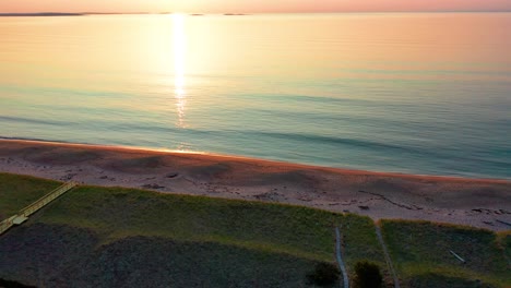Luftaufnahme-Eines-Sonnenuntergangs-über-Einem-Strandhaus-In-Saco,-Maine,-Mit-Farben,-Die-Sich-In-Den-Meereswellen-Spiegeln,-Und-Ferienhäusern-Entlang-Der-Atlantikküste-Von-Neuengland