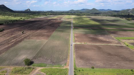 An-Aerial-Drone-Shot-of-a-Blue-Toyota-CHR-Vehicle-Driving-Along-a-Straight-Road-in-the-Countryside-of-Lopburi,-Thailand