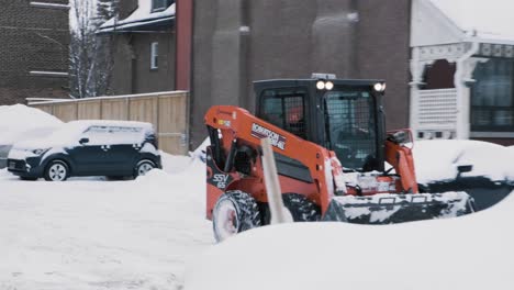 Handheld-shot-of-a-city-worker-removing-large-amounts-of-snow-from-a-parking-lot-in-Ottawa,-Ontario,-Canada