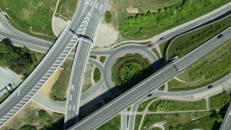 Transportation-themed-aerial-static-drone-footage-capturing-intricate-highway-junction-with-cars-navigating-complex-roundabouts-and-intersecting-roads-with-cars