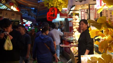 La-Gente-Deambula-Por-Un-Encantador-Callejón-Lleno-De-Puestos-De-Comida-Y-Tiendas-De-Regalos-Dentro-De-La-Antigua-Calle-Jiufen,-Vendedores-Que-Ofrecen-Muestras-Y-Degustaciones-De-Comida,-Un-Punto-Turístico-En-Taiwán