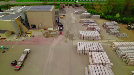 Aerial-view-of-a-busy-industrial-shipping-yard-with-forklifts-loading-flatbed-semi-truck