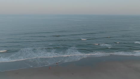 Aerial-shot-of-continuous-waves-approaching-the-shore-of-beach