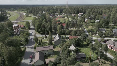 Rural-Swedish-railway-town-aerial-arcs-towards-old-Nordic-water-tower