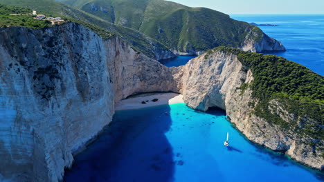 Aerial-drone-fly-Navagio-Beach-Greece-blue-bay-green-cliff-travel-sea-landscape