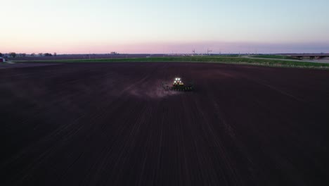 Aerial-View-behind-of-Tractor-Plowing-a-Field-at-Dusk