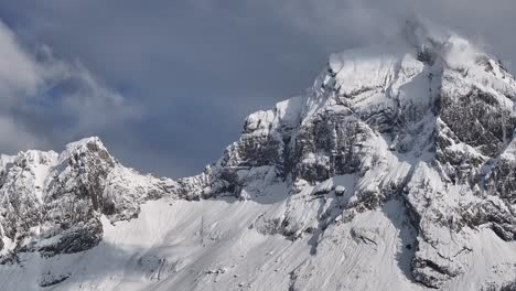 Aerial-view-of-the-snow-covered-Fronalpstock-peak-with-rugged-cliffs-and-a-partly-cloudy-sky-in-Glarus-Nord,-Switzerland