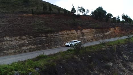 Toma-Aérea-De-Un-Porsche-Cayman-En-Movimiento-En-Una-Sinuosa-Carretera-Colombiana