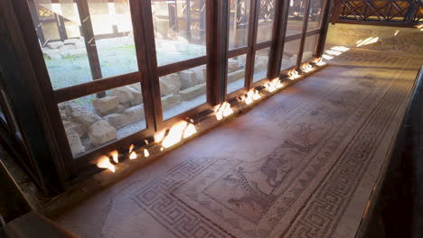 Ein-Blick-Auf-Den-Mosaikboden-In-Der-Nähe-Einer-Glaswand-Im-Haus-Des-Dionysos,-Mit-Sonnenlicht,-Das-Hereinströmt