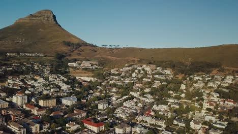 Drone-Dando-Vueltas-Alrededor-De-Un-Barrio-Urbano-Con-La-Montaña-De-La-Cabeza-De-León-Al-Fondo-En-Ciudad-Del-Cabo,-Sudáfrica
