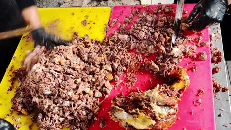 Chef-cutting-cooked-pieces-of-meat-for-pilaf-with-a-knife-on-a-cutting-board