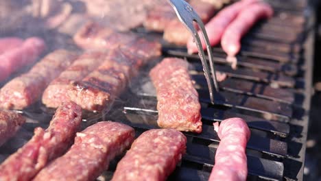 Cooking-Sausages-And-Meat-On-Grill-Outdoor-With-Carving-Fork