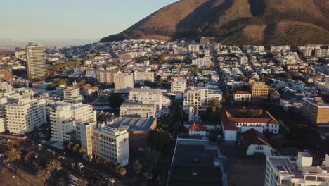 Eine-Drohne-Fliegt-Nach-Oben-Und-Enthüllt-Die-Stadtgebäude-In-Der-Nähe-Der-Küste-Von-Kapstadt,-Südafrika