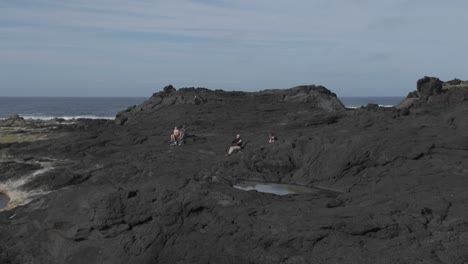 Schroffe-Schwarze-Vulkangesteine-Bei-Mosteiros,-Sao-Miguel-Mit-Spärlichem-Grün-Und-Meereskulisse,-Bewölkter-Himmel