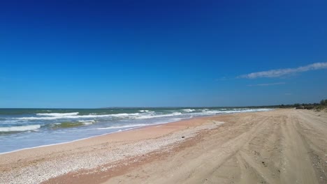 Playa-Vacía-Con-El-Telón-De-Fondo-De-Cielo-Azul-Y-Mar-Salvaje-4k