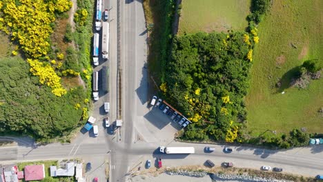 Aerial-Bird-Eye-View-Of-Parked-Lorries-Leading-To-Pier-With-Ferry-Boat-Waiting-At-Big-Island-of-Chiloé,-Chile