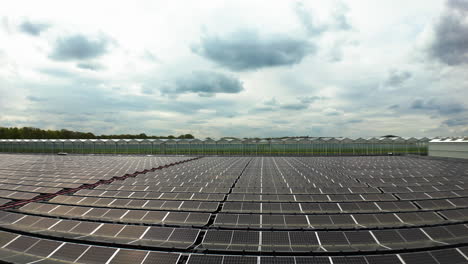 Granja-De-Paneles-Solares-Que-Proporciona-Energía-Para-Invernaderos-Industriales-Masivos,-Vista-Aérea-De-Drones