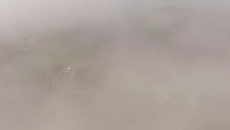 Aerial-drone-moves-through-clouds-above-grassland-and-farmland-in-midwest-of-United-States