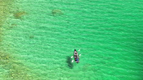 Aerial-top-view-of-a-small-boat-floating-on-the-clear,-emerald-waters-of-Eibsee-in-Grainau,-Germany