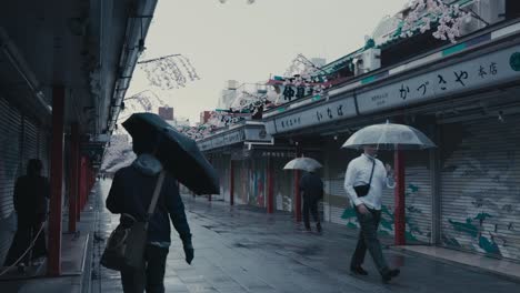 People-With-Umbrella-Walking-In-The-Nakamise-dori-Street-With-Close-Stores-During-Rainy-Day-In-Tokyo,-Japan