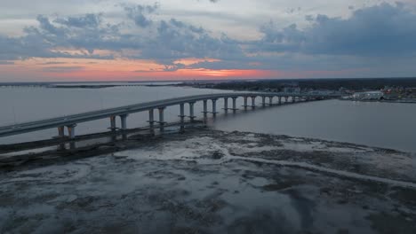 Aerial-drone-panning-shot-over-a-long-bridge-along-the-bay-area-after-sunset
