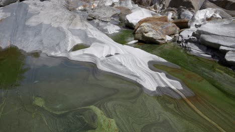 Lavertezzo-stream-flows-across-grey-rocks-smoothing-out-the-stones-in-a-patterned-structure