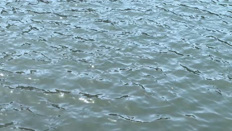 Glistening-water-surface-shimmering-under-daylight,-close-up-of-small-waves-and-ripples